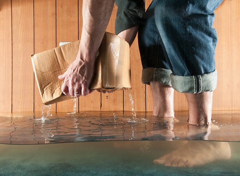 Man lifting cardboard box in flooded basement, low section