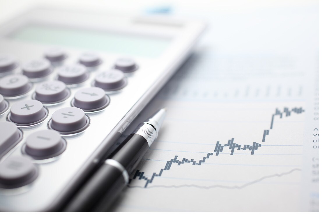 Calculator and ballpoint pen on stock market data chart.