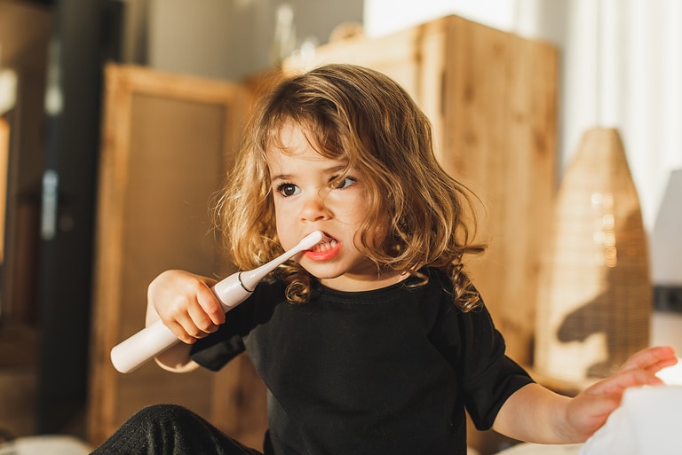 Sweet child with curly hair. Daily routine, healthy lifestyle and a useful hygienic habit. Home education, sustainable parenting. Happy moments.