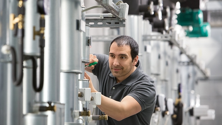 Fachhandwerker optimiert Heizungspumpe im Heizkeller des Gebäudes