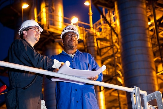 Multi-ethnic engineers working at chemical plant at night.