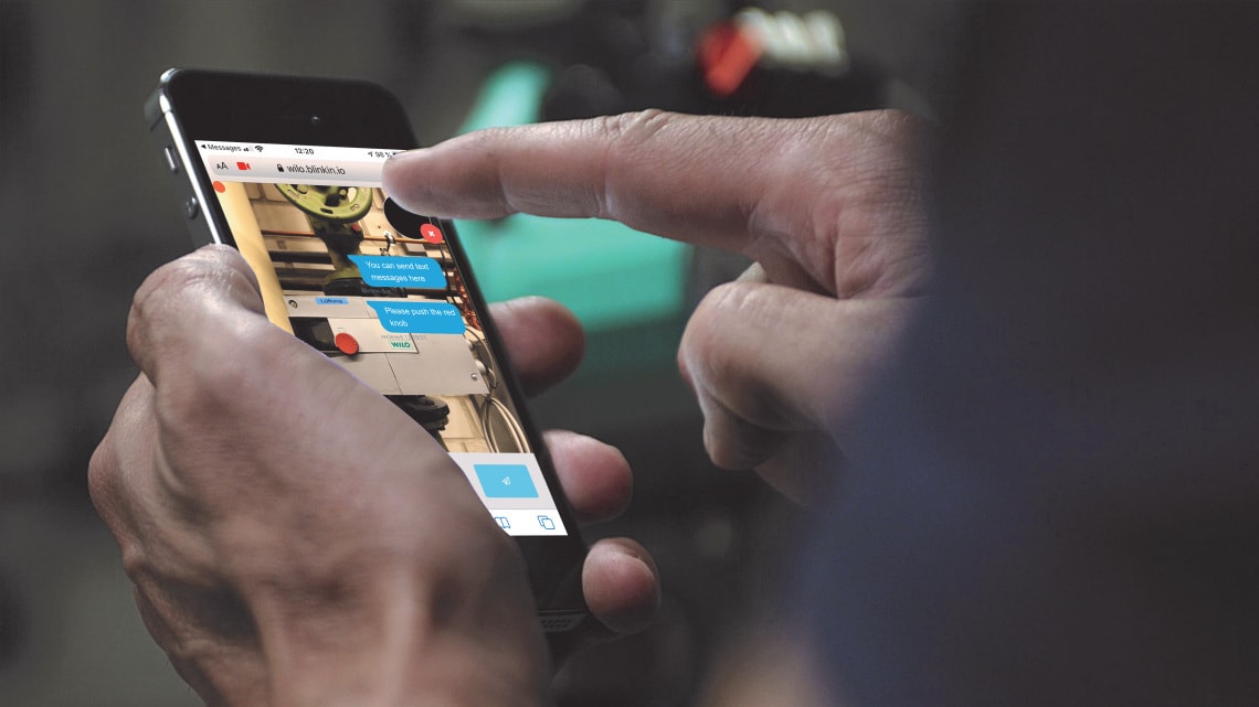 Installer is holding a smart phone in his hand, on the screen you can see the Wilo-Live Assistant in use
