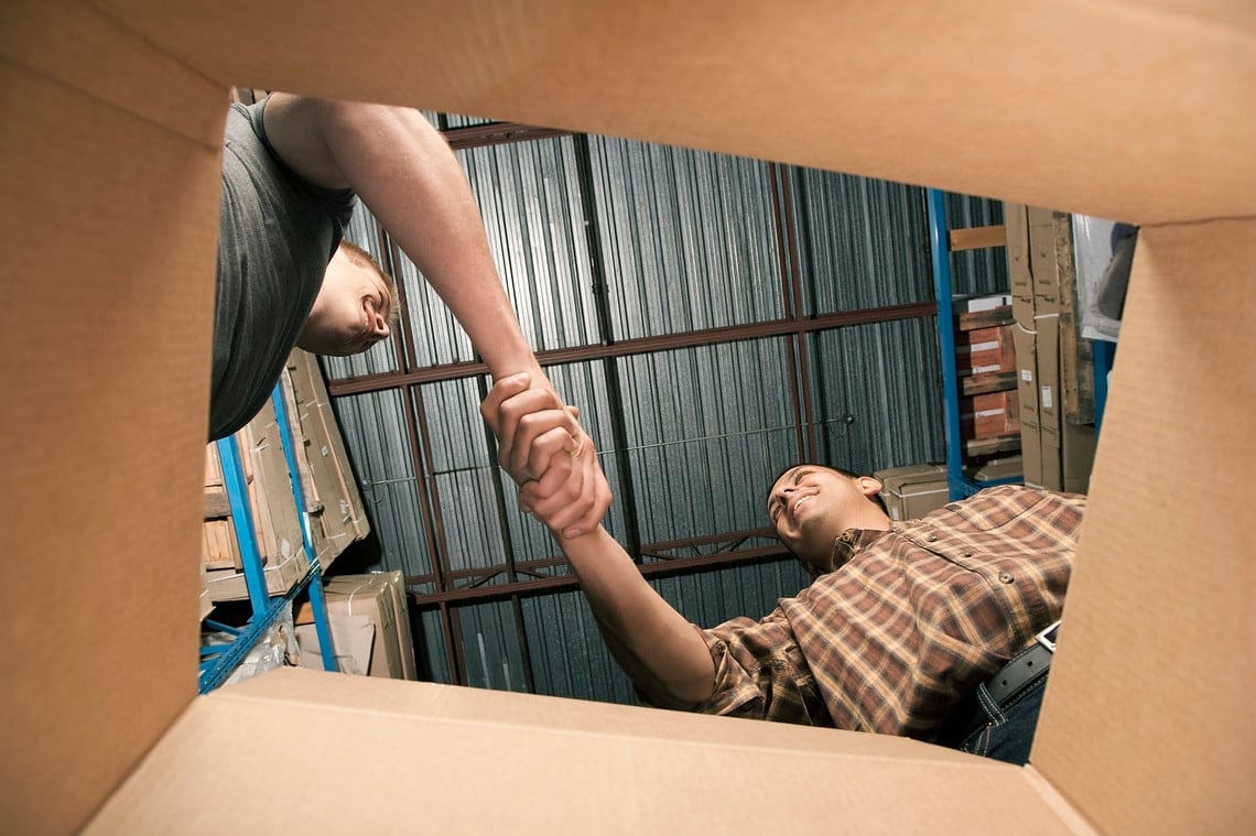 Man shaking hands over cardboard box in warehouse