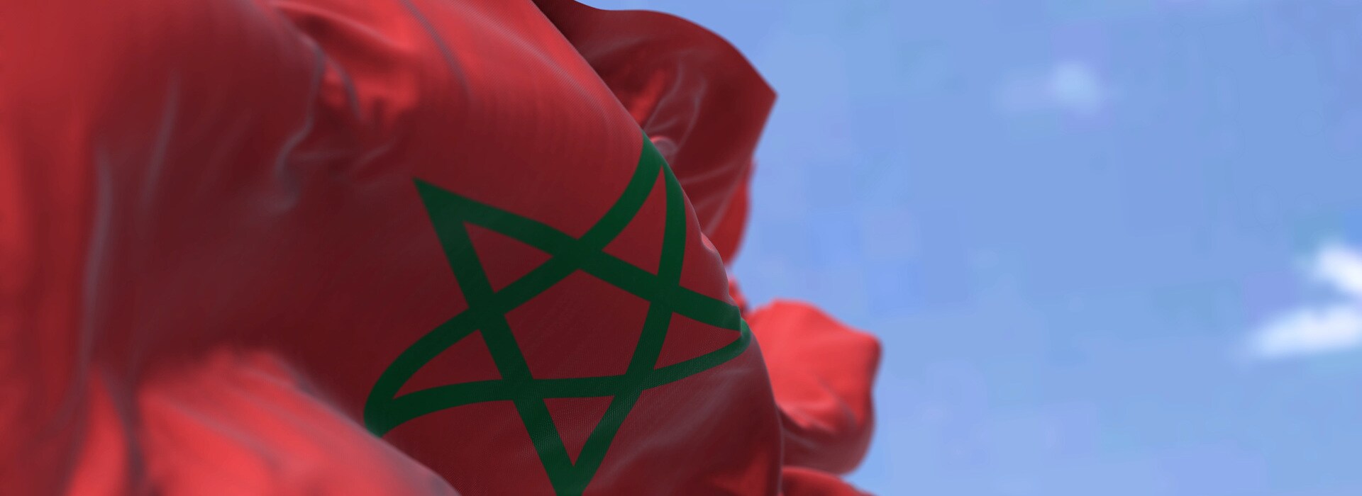 Detail of the national flag of Morocco waving in the wind on a clear day. North African Country. Patriotism. Selective focus.