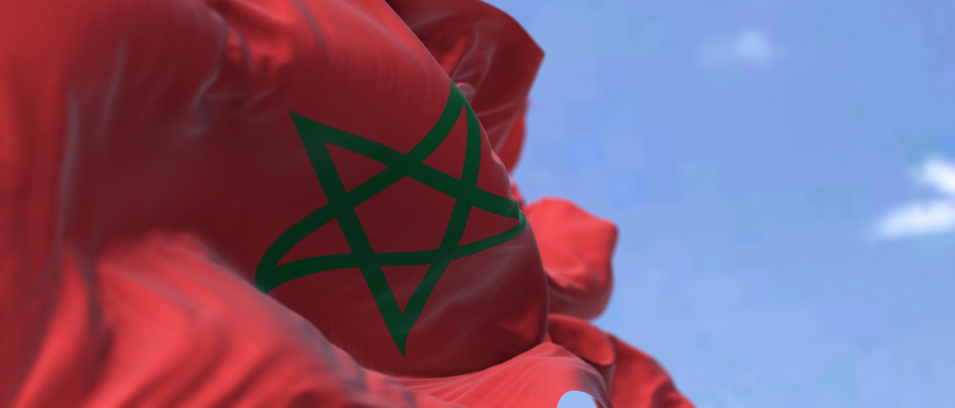 Detail of the national flag of Morocco waving in the wind on a clear day. North African Country. Patriotism. Selective focus.