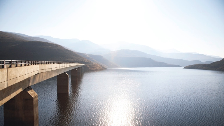 View of bridge going over Katse Dam with sun reflecting off water