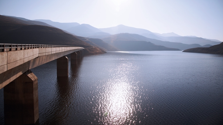 View of bridge going over Katse Dam with sun reflecting off water