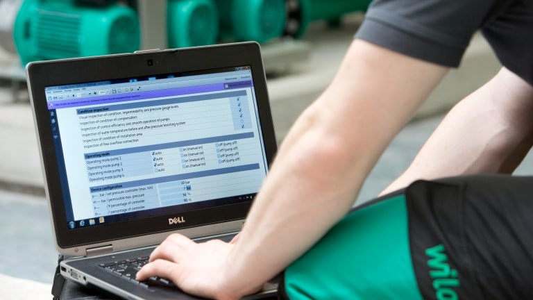 Service technician is sitting in front of a laptop