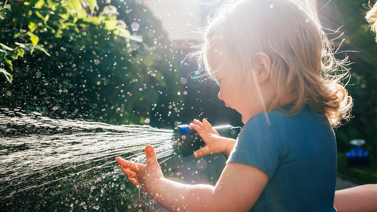 Little child watering the garden with rainwater harvesting system