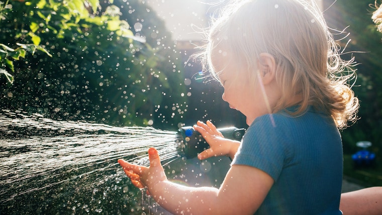 Little child watering the garden with rainwater harvesting system