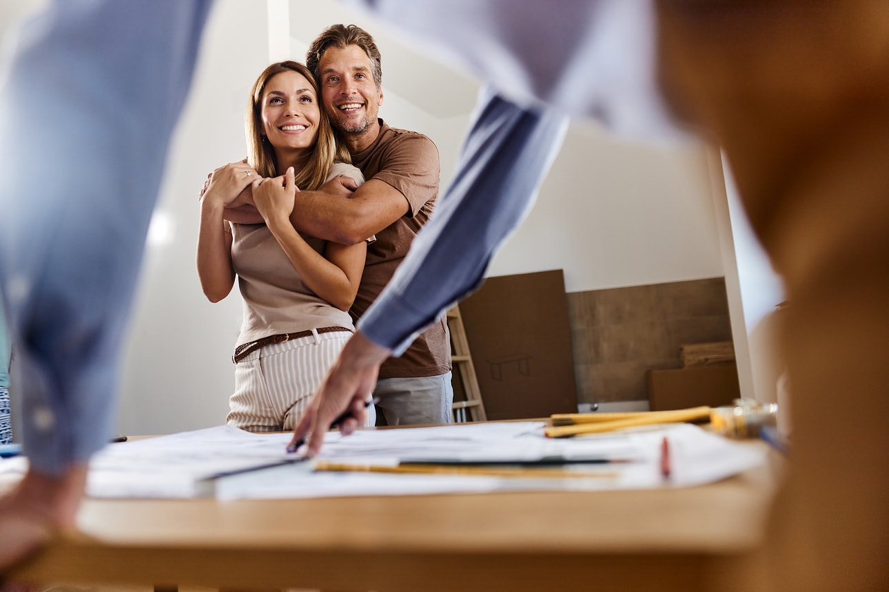 Couple amoureux discutant de plans de logement avec un entrepreneur à l’intérieur de leur appartement
