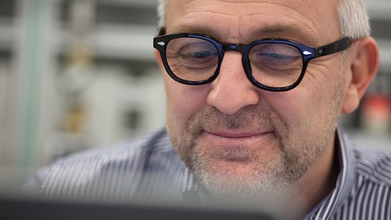 smiling man with glasses in front of a laptop, Service technician Thorsten Stolpmann