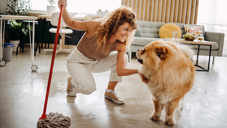 A woman mops the floor inside her house using rainwater 