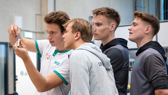 ein-auszubildender-von-wilo-erklaert-drei-nachwuchsruderern-des-team-deutschland-achters-ein-baustueck-einer-wilo-pumpe