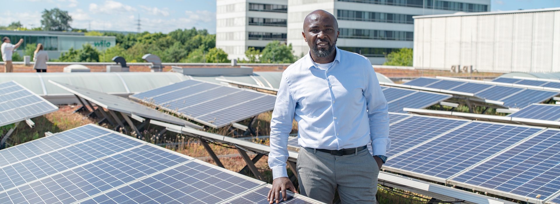 Cebastien Foumouo Tsakou zwischen Photovoltaikmodulen auf dem Dach der Smart Factory von Wilo in Dortmund