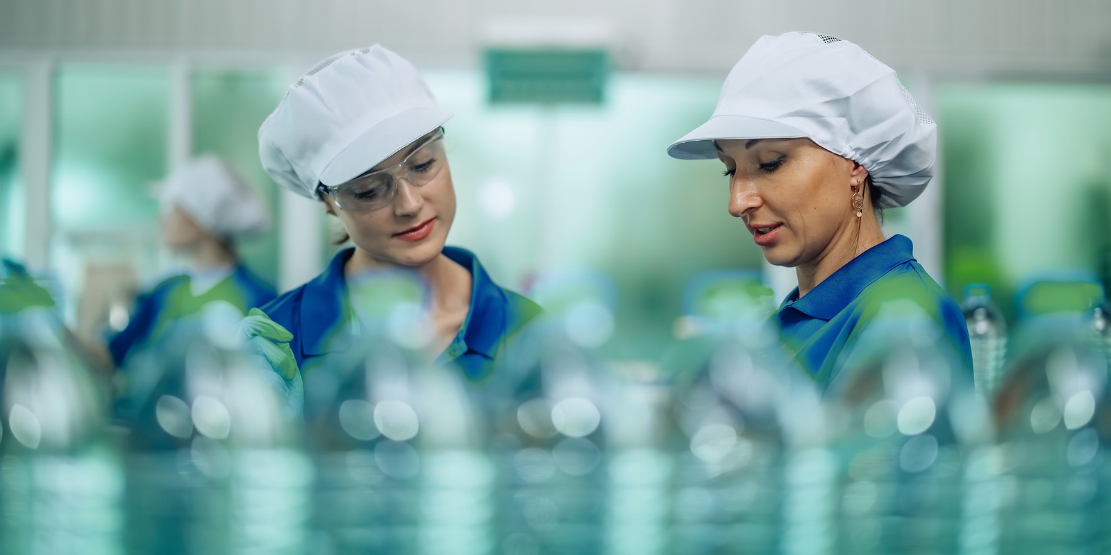 Nowoczesna linia produkcyjna w zakładzie przetwórstwa spożywczego, na której butelki są automatycznie napełniane i zakręcane.