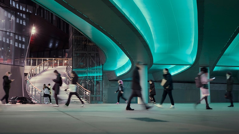 Urban street scene with people walking and heavily sealed surfaces; wastewater transport remains invisible, but is an indispensable part of the urban infrastructure.