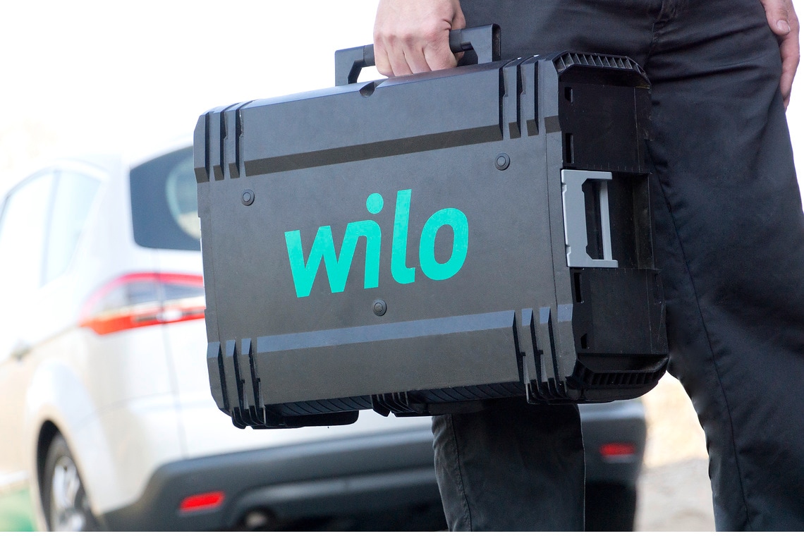 Service technician (Mr. Muslu) with a Wilo tool case in his hand, in the background is a Wilo car